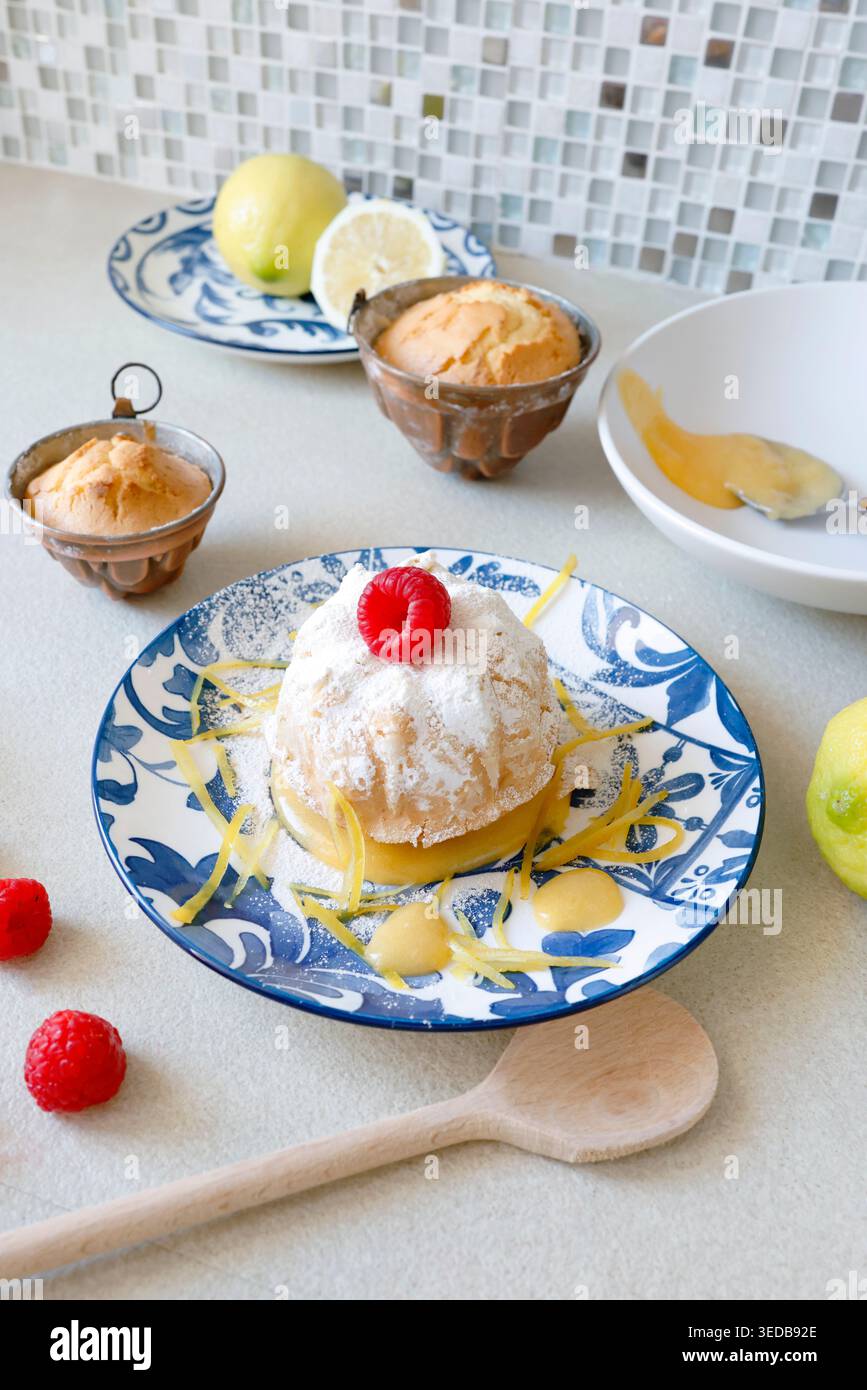 Mini gâteau citron Bundt avec Curd et framboises. La tendance de la pâtisserie méditerranéenne authentique met l'accent sur les ingrédients biologiques naturels et les agrumes vibrants Banque D'Images