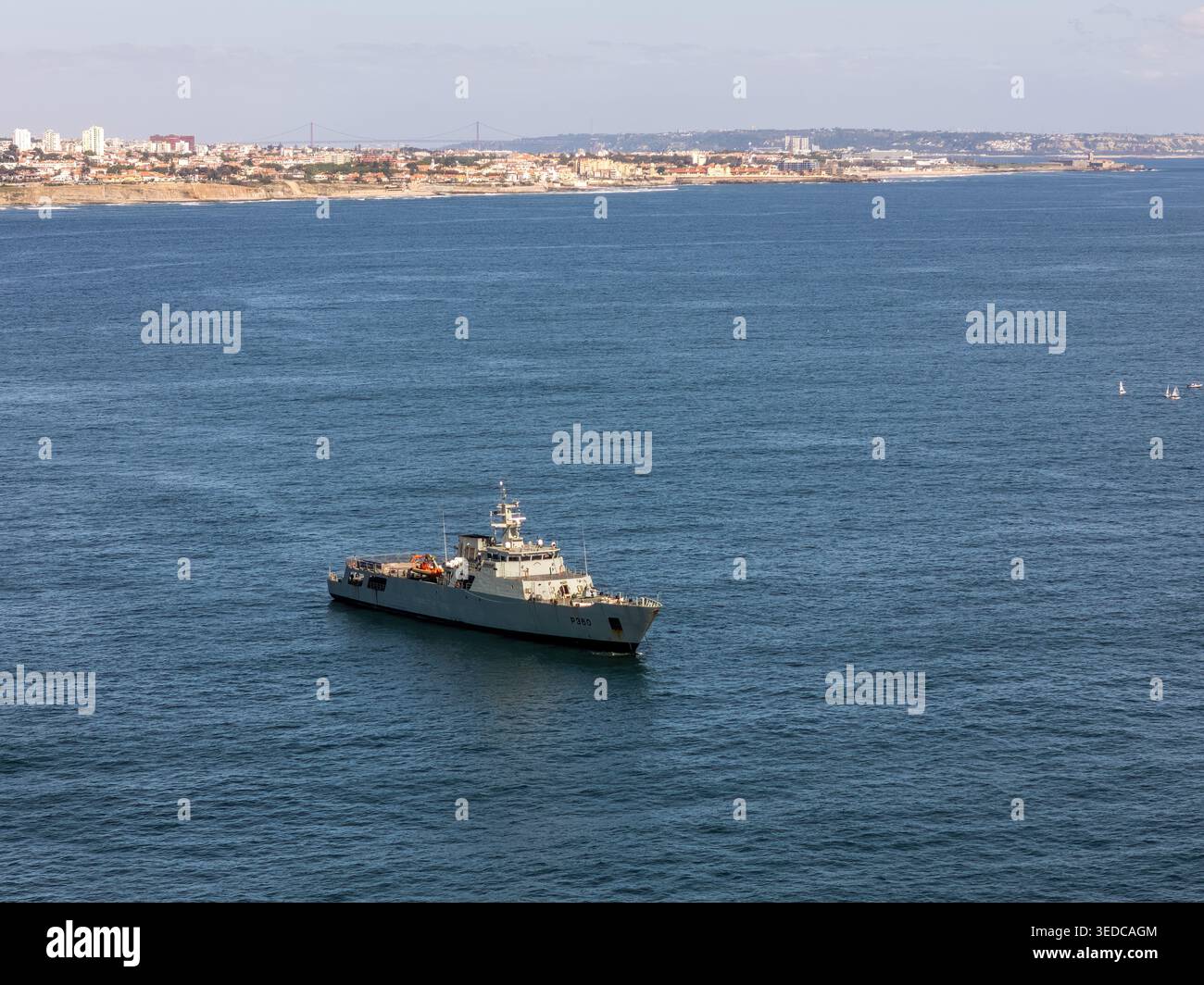 Vue aérienne d'un navire de patrouille navale gris naviguant sur l'océan bleu avec l'horizon côtier en arrière-plan Cascais, Portugal. Banque D'Images