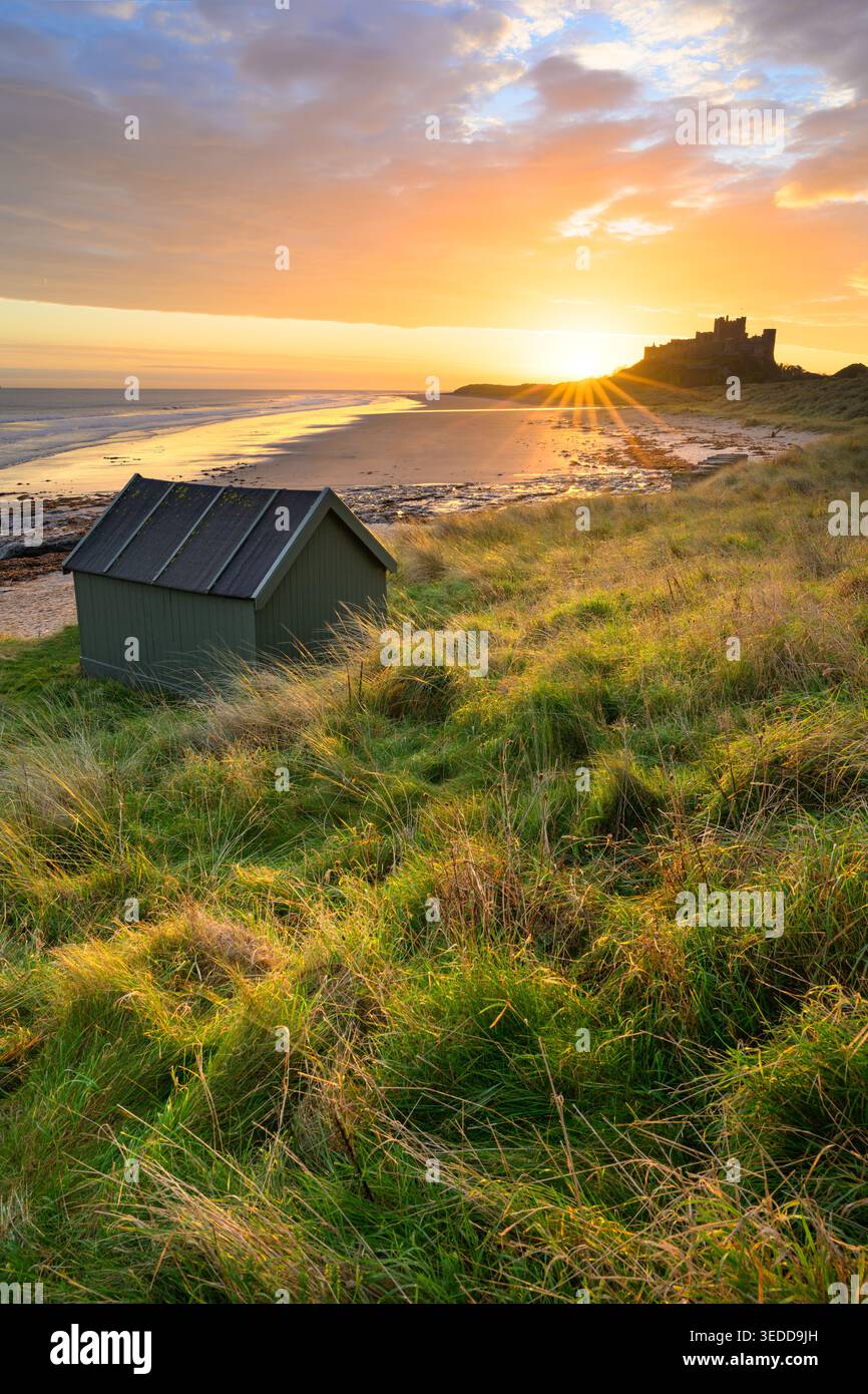 Cabane en bois au château de Bamburgh avec un beau lever de soleil doré sur la côte du Northumberland, Royaume-Uni. Banque D'Images