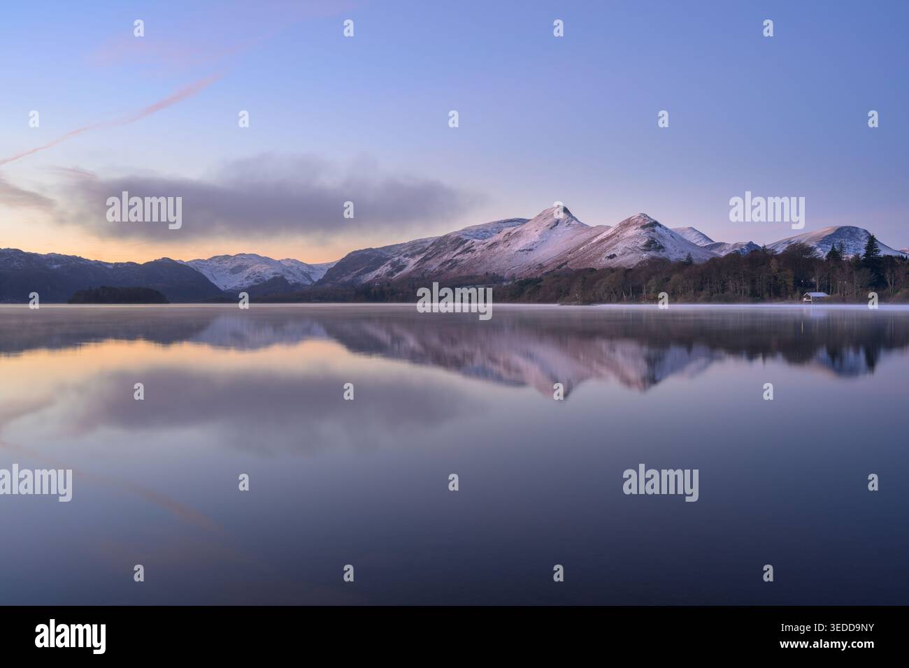 Reflets calmes d'hiver dans le lac Derwentwater au lever du soleil avec de la neige sur les montagnes, Lake District, Angleterre, Royaume-Uni. Banque D'Images