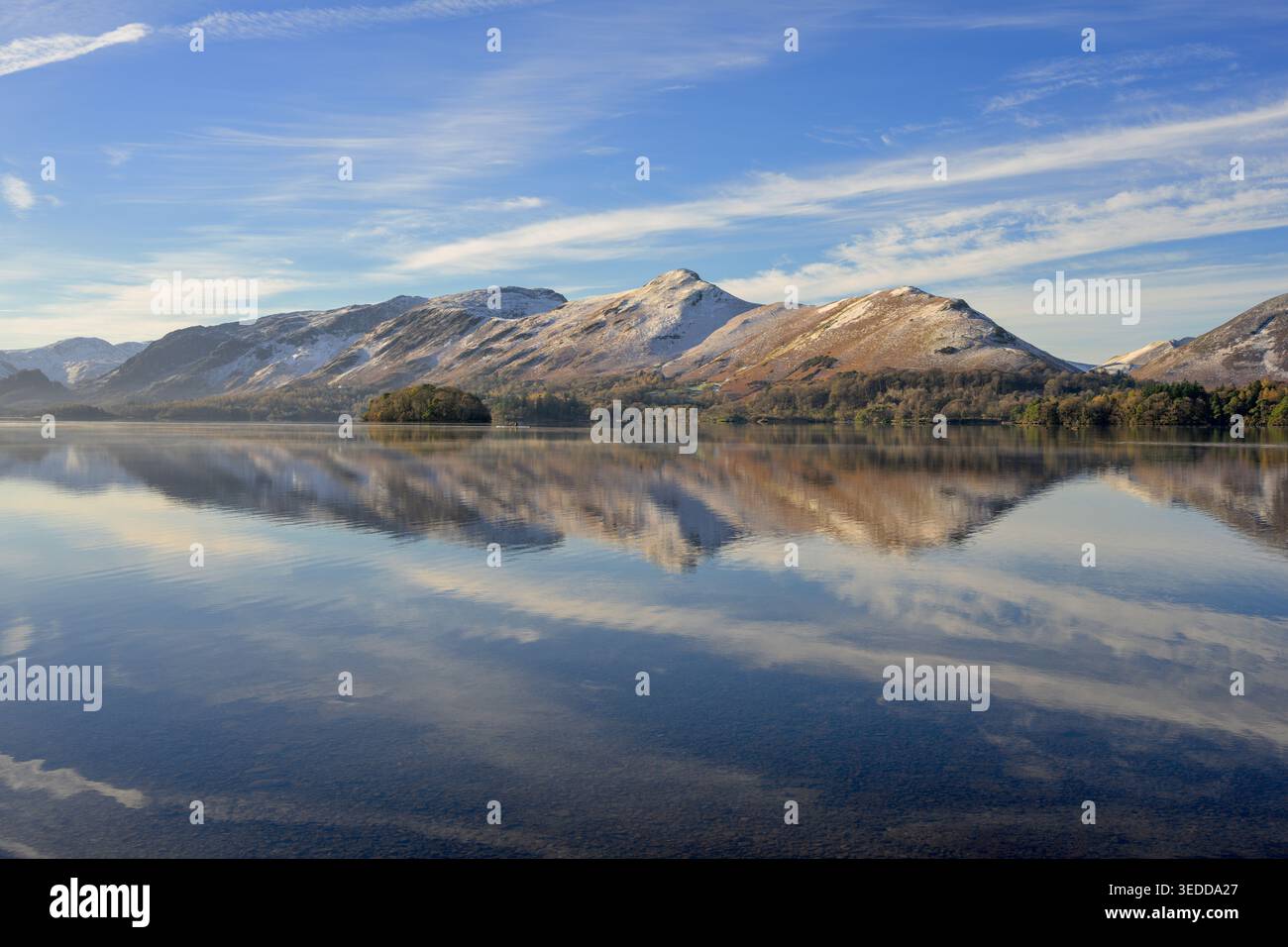 Un matin d'hiver croustillant sur les rives de Derwentwater surplombant les montagnes enneigées reflétant dans l'eau calme. Lake District, Angleterre, Royaume-Uni. Banque D'Images