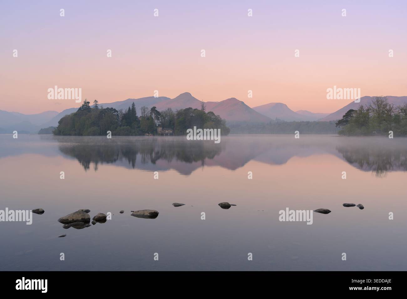 Vue brumeuse de Derwentwater au lever du soleil avec des reflets par un matin de printemps calme dans le parc national du Lake District. Banque D'Images