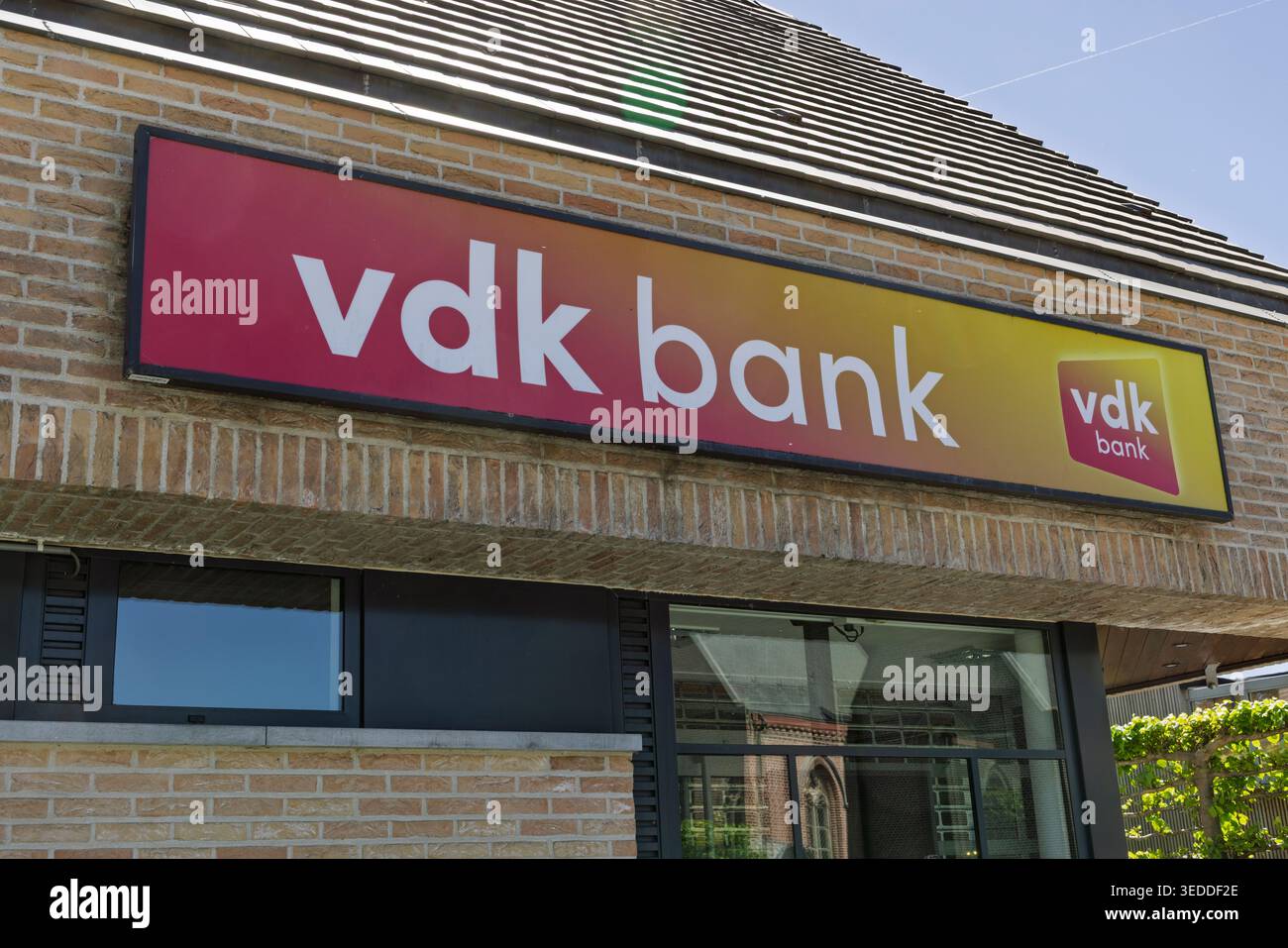 Schelderode, Belgique. 01 mai 2026. Vue rapprochée du logo moderne rouge et jaune de VDK Bank sur la façade en brique d'une succursale locale. Banque D'Images