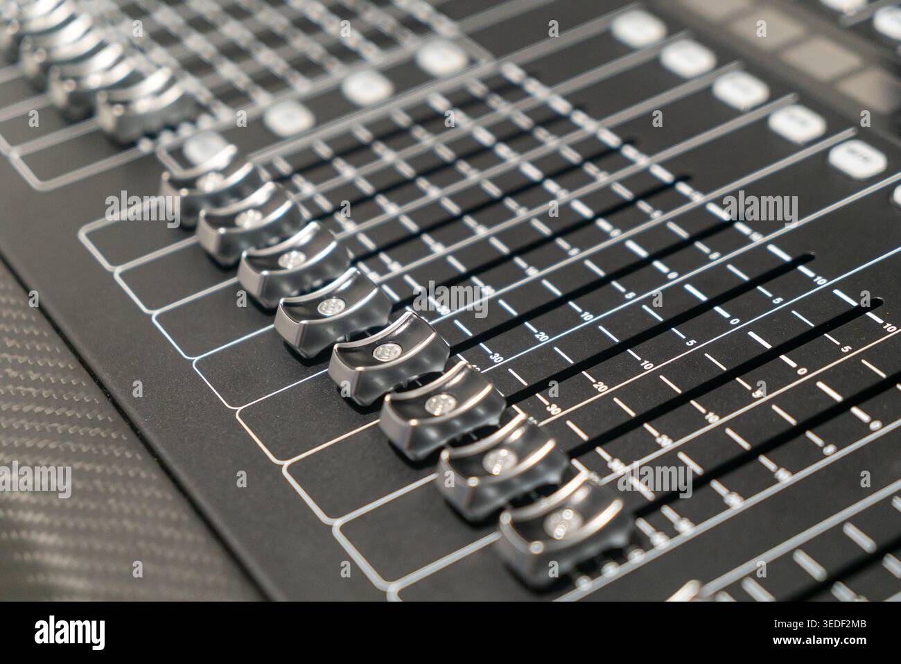 Vue rapprochée d'une console de mixage audio professionnelle présentant diverses commandes, curseurs et boutons utilisés dans la production sonore et l'ingénierie musicale. Banque D'Images