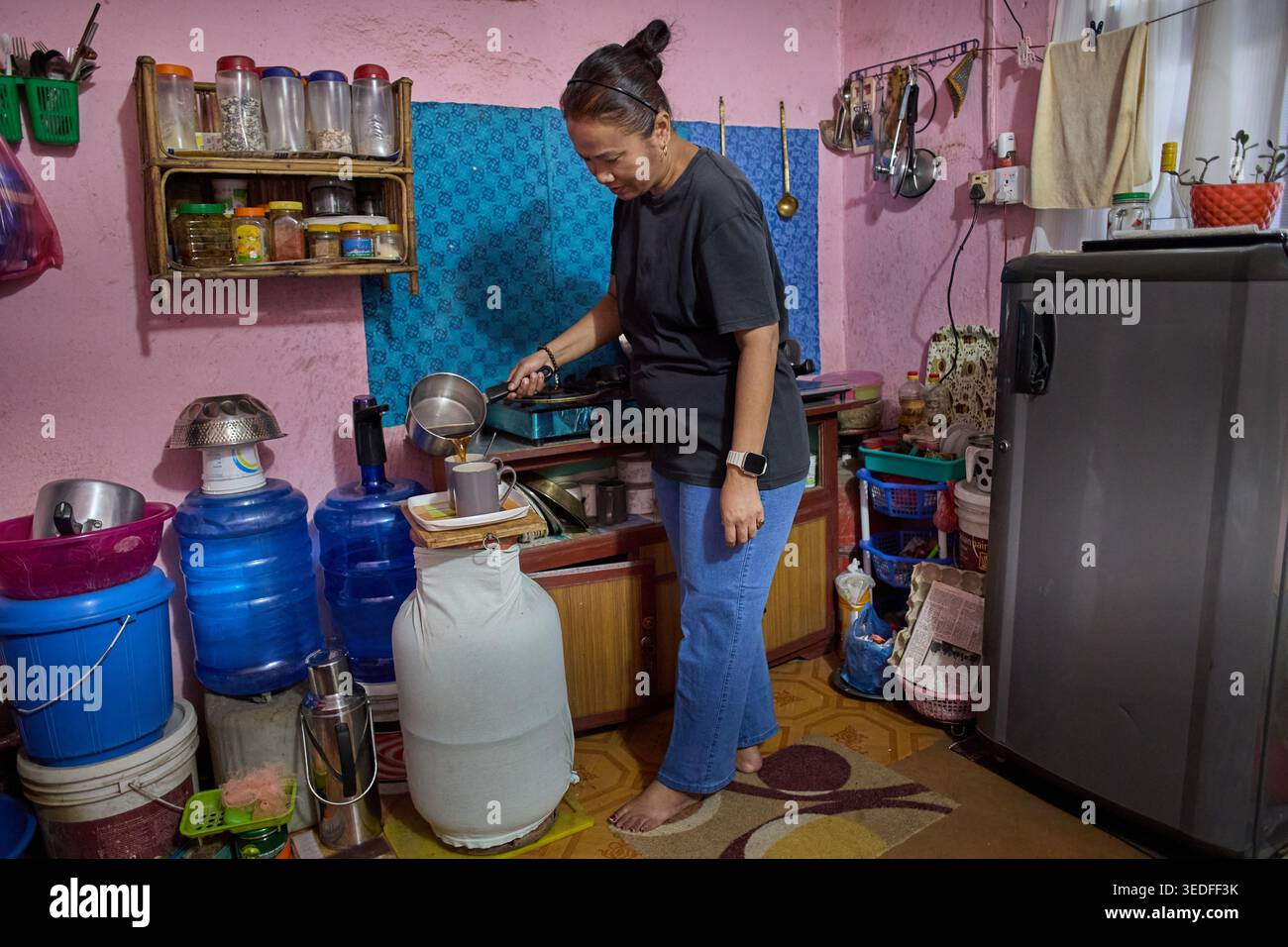 Une femme engagée dans les tâches ménagères dans une cuisine colorée, mettant l'accent sur la vie quotidienne et les activités domestiques Banque D'Images