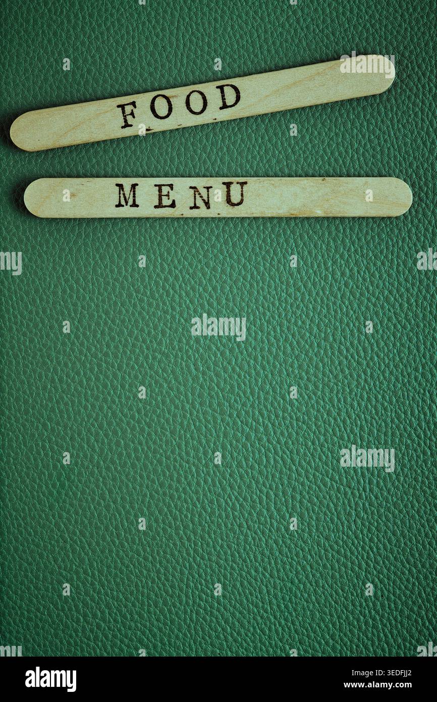 MENU ALIMENTAIRE à composition verticale sur bâtons en bois sur une surface en cuir vert. Copier l'espace Banque D'Images