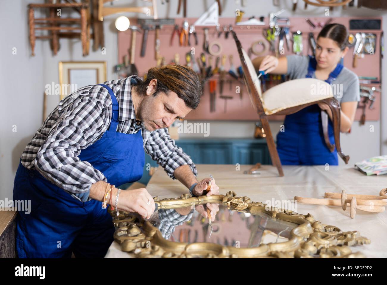 Menuisier masculin travaillant sur la restauration du miroir vintage en atelier Banque D'Images