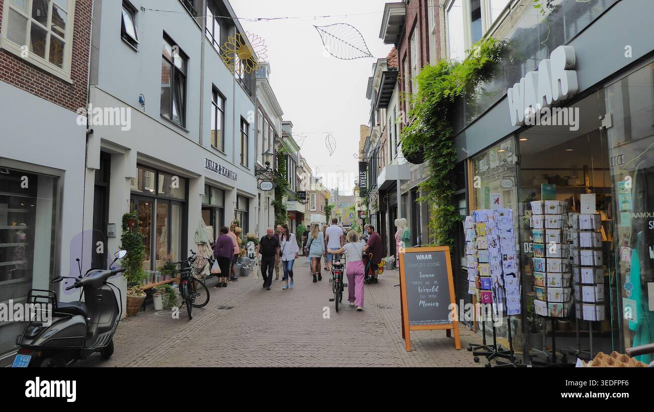 Les gens se promènent dans une rue commerçante étroite bordée de petites boutiques et de devantures de magasins dans un cadre urbain animé. Banque D'Images
