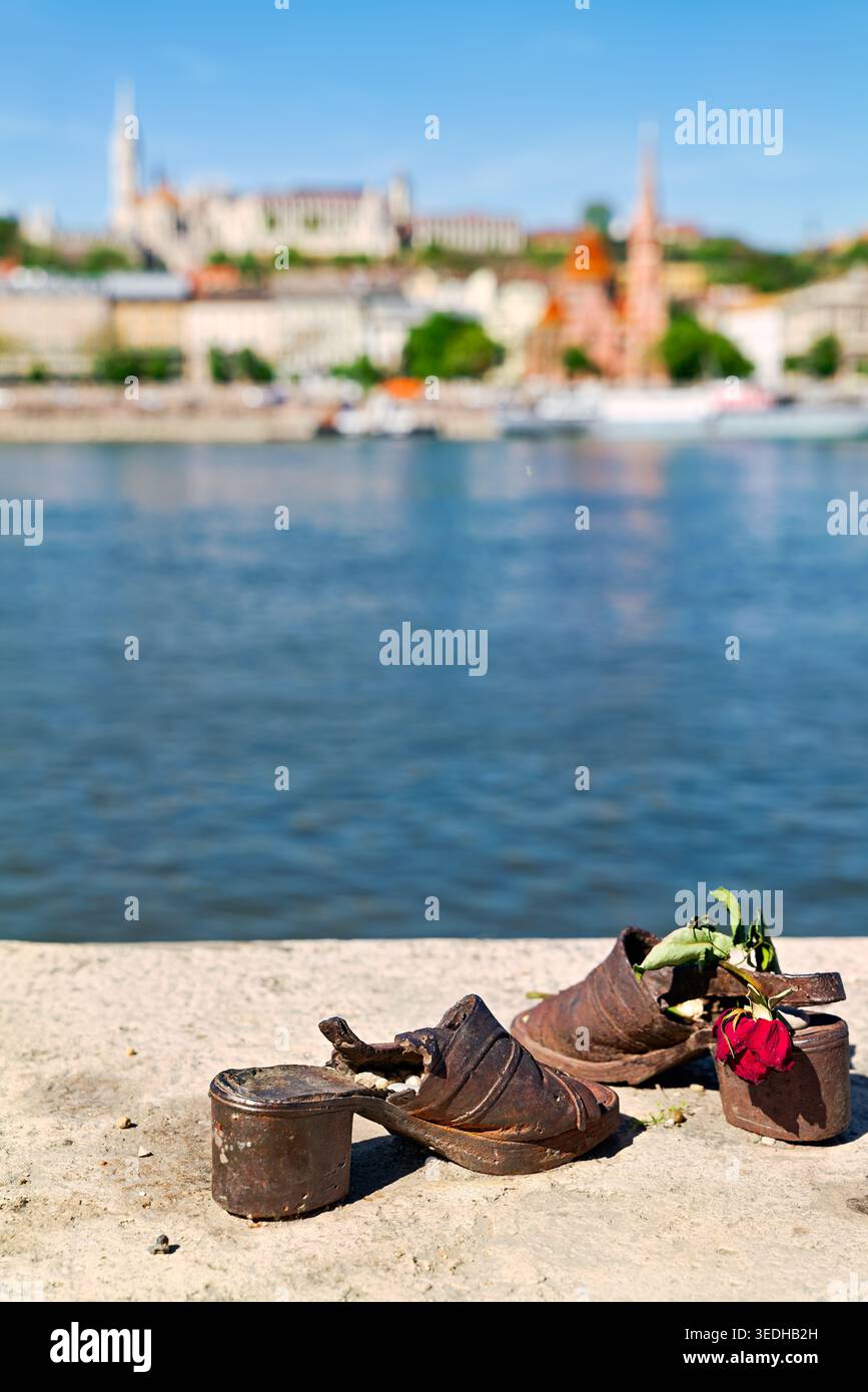 Un mémorial avec de vieilles chaussures placé sur la rive à Budapest. Ce site honore les victimes de la guerre et montre des fleurs à proximité. Banque D'Images