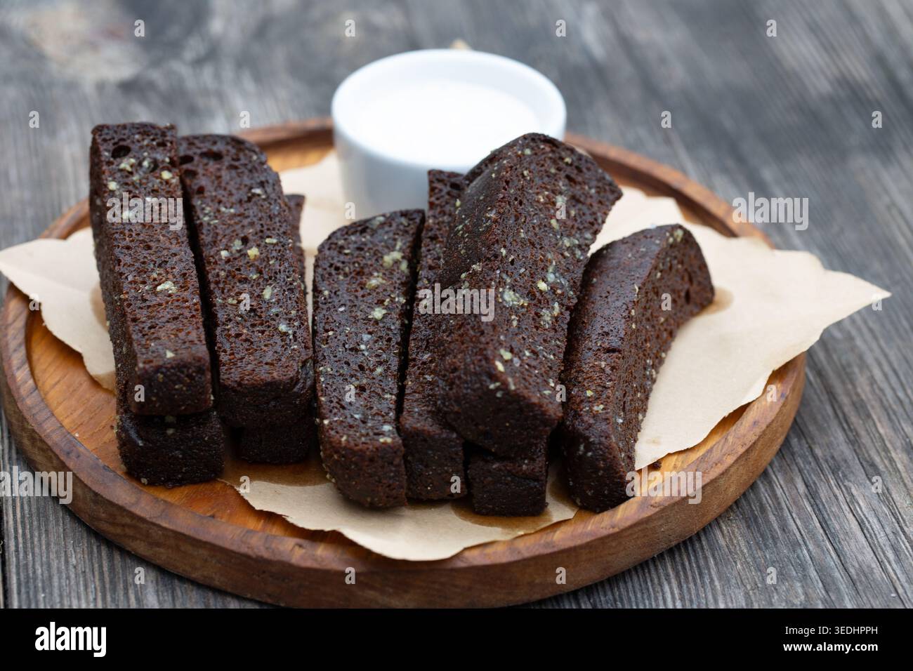 Apéritif de pain à l'ail noir avec sauce blanche sur une planche de bois. Banque D'Images