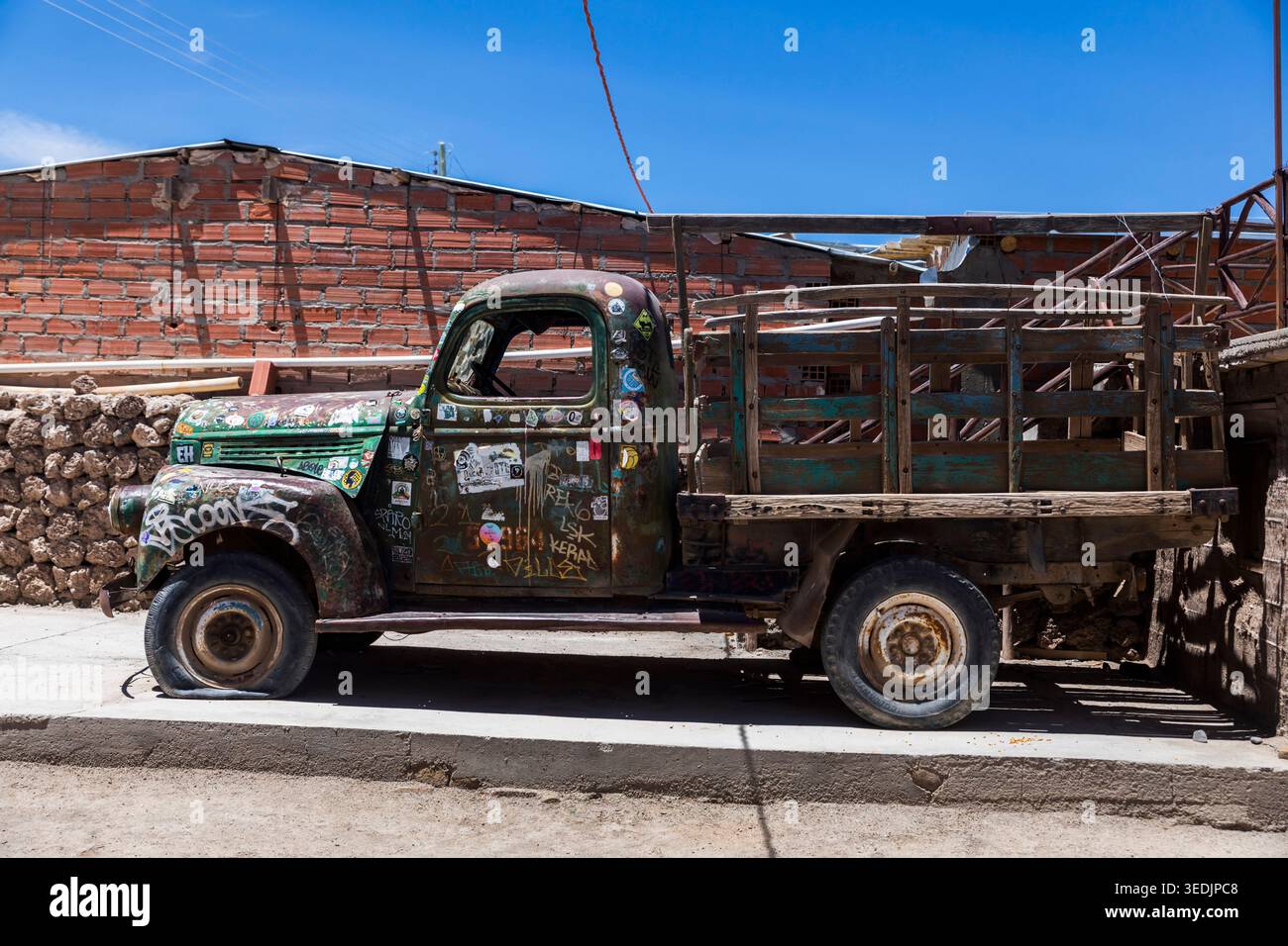 Un camion vintage lourdement altéré, couvert d'autocollants, de graffitis et de décennies de rouille, est stationné le long d'une rue à Uyuni, en Bolivie. Le véh Banque D'Images