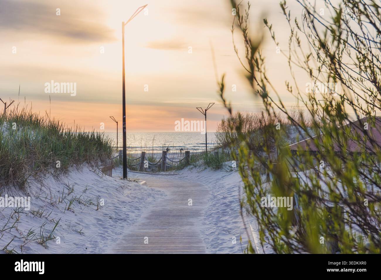 Mer Baltique calme sur la promenade en bois à travers les dunes de sable vers la mer Baltique au coucher du soleil à Liepaja. Voyage, atmosphère côtière et lenteur saisonnière Banque D'Images