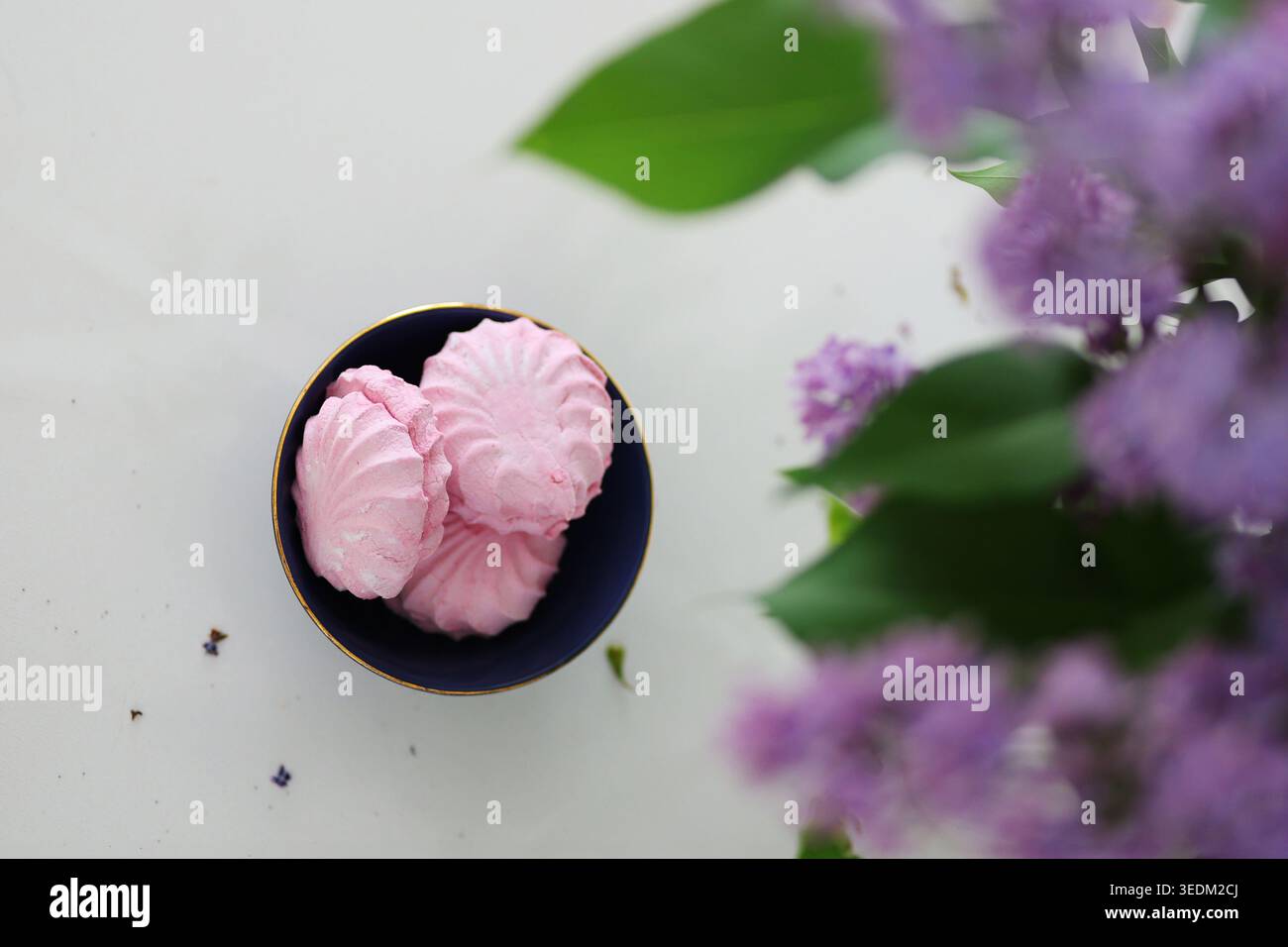 Composition printanière romantique avec desserts roses, bouquet floral et tasse faite main dans un intérieur minimaliste lumineux. Banque D'Images