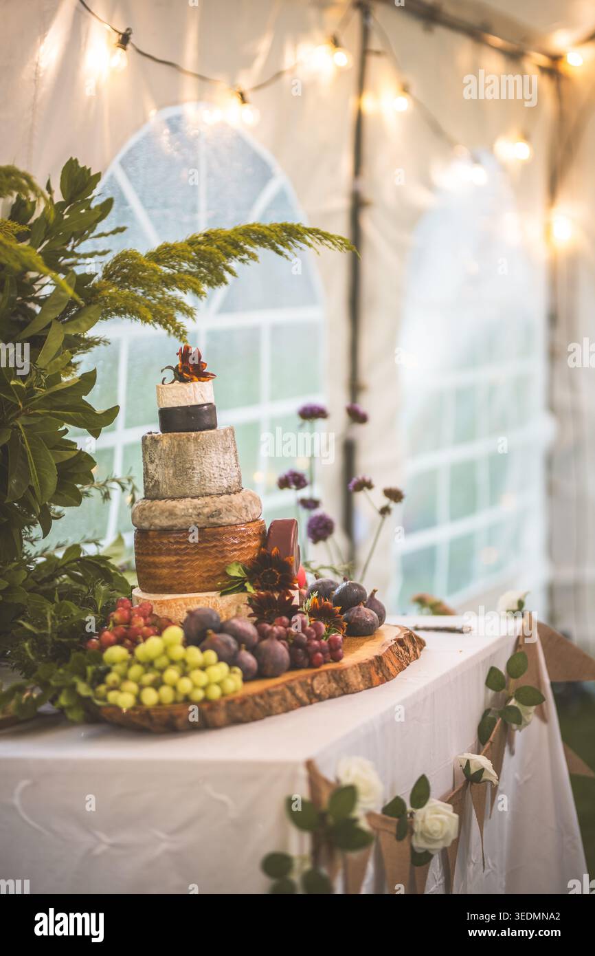 Un beau gâteau à la roue de fromage est la pièce maîtresse de cette élégante réception de mariage, entourée de fruits frais Banque D'Images
