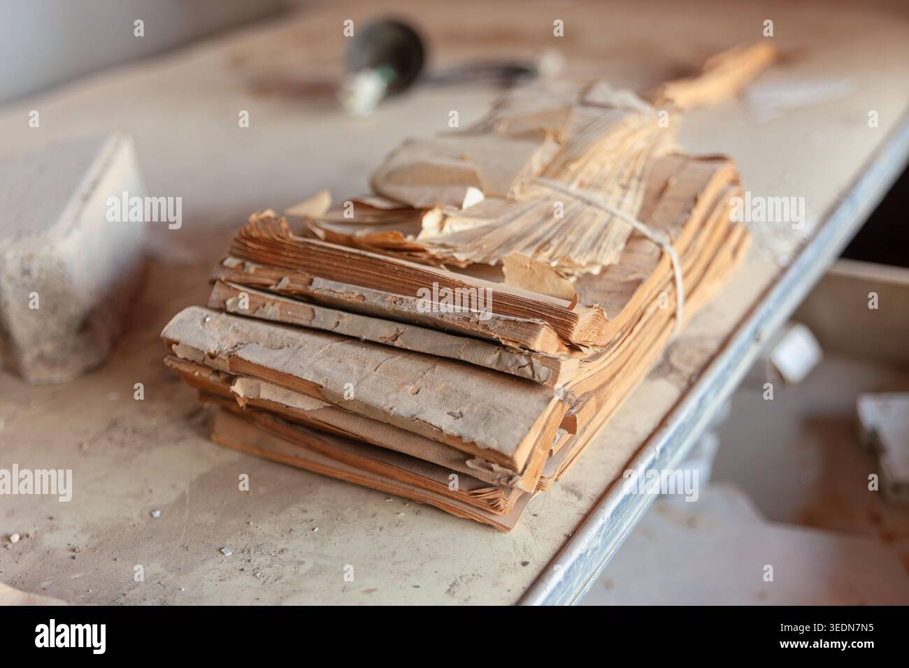 Une pile de livres de comptes fortement déformés et friables, solidement ficelée, repose sur une surface en bois poussiéreuse. Banque D'Images
