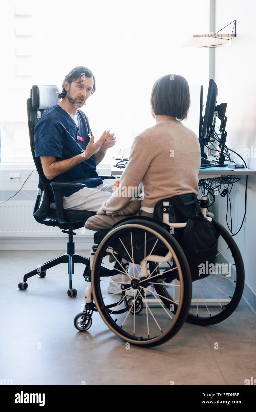Expert médical masculin discutant avec une patiente ayant un handicap physique à l'hôpital Banque D'Images