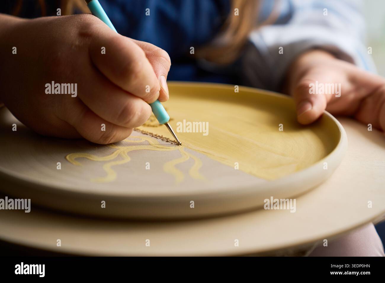 Vue détaillée d'un outil sgraffito pointu gravant des conceptions sur la surface d'argile brute Banque D'Images