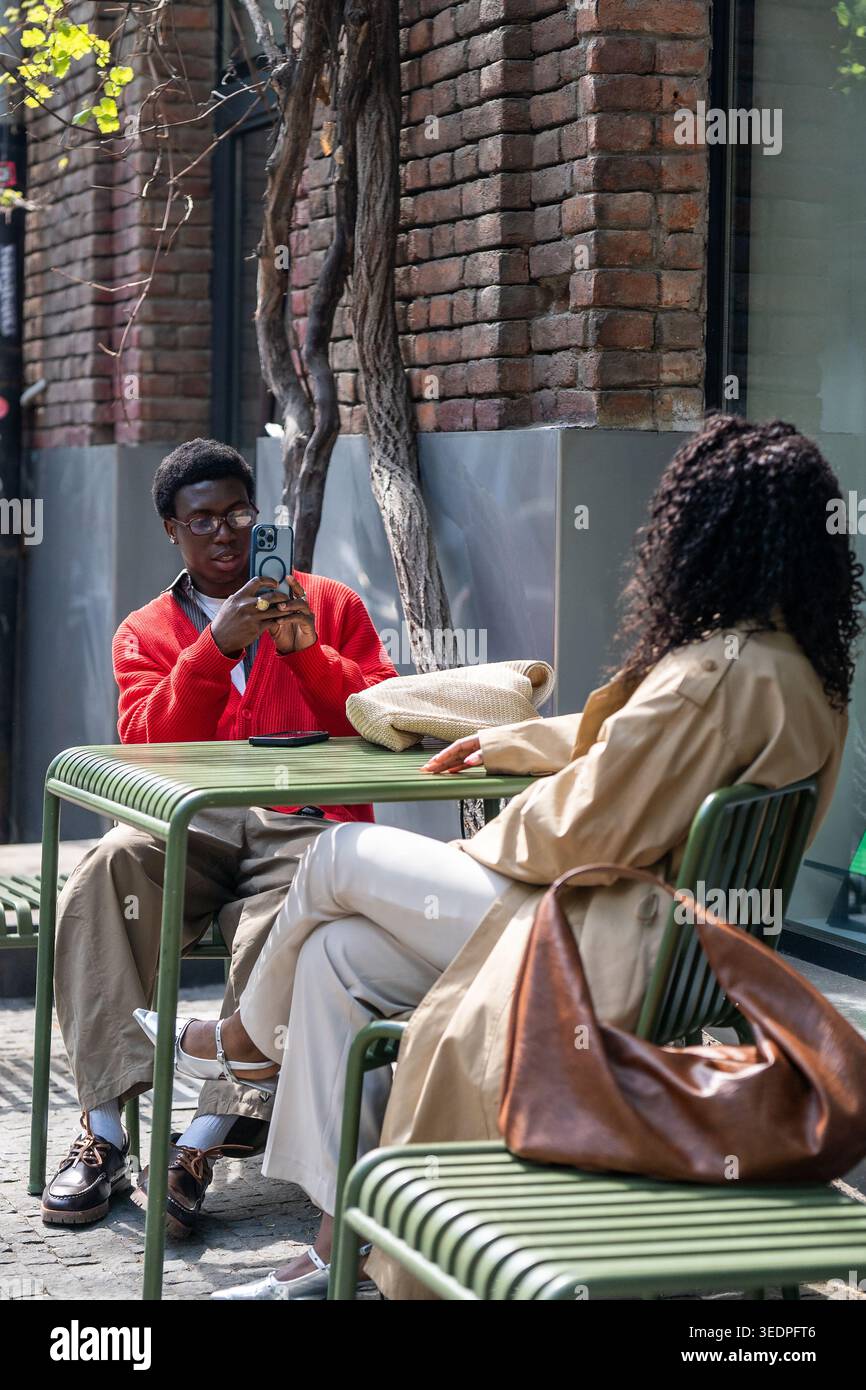 Couple homme et femme amis assis se relaxant dans le café de la ville en plein air et prendre des selfies sur smartphone. Banque D'Images