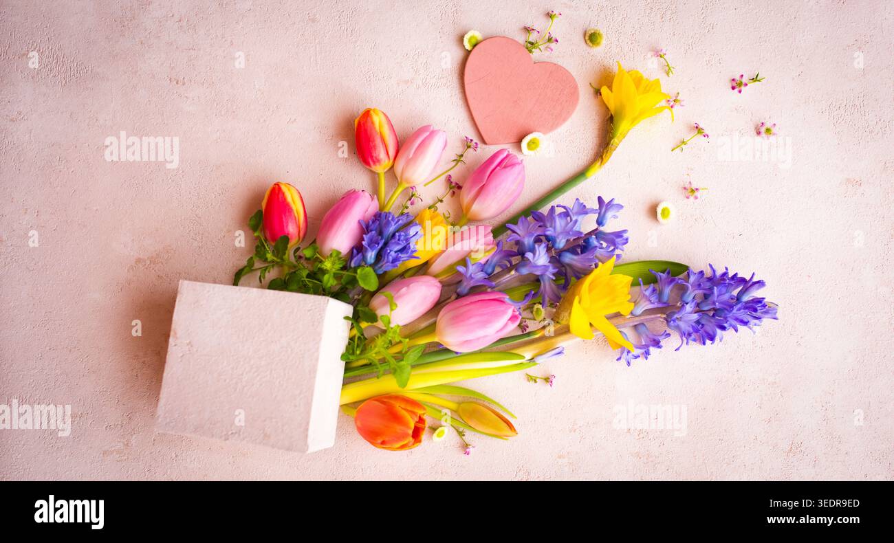 Nature morte avec des fleurs de printemps colorées pour la fête des mères sur fond rose tendre pour les salutations de fête des mères. Banque D'Images