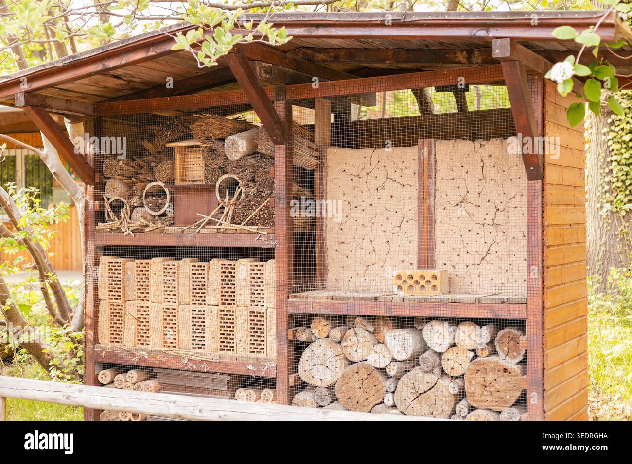 Un hôtel d'insectes se dresse dans un jardin, conçu pour offrir un abri aux insectes. Il est fabriqué à partir de bois, de bâtons et de matériaux naturels. La structure est pleine Banque D'Images