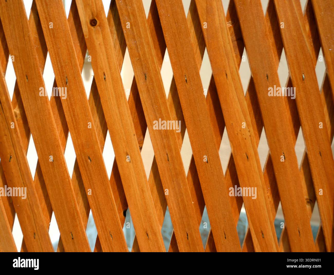 Treillis en bois avec lattes diagonales répétitives formant des formes de diamant, créant un fond géométrique décoratif ou un écran pour les jardins, les clôtures et les détails architecturaux Banque D'Images