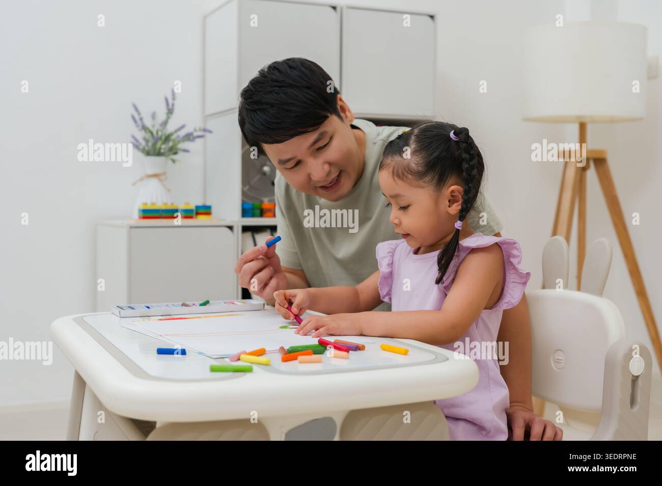 père et enfant fille dessin et peinture avec des pastels à l'huile colorés sur papier à la maison Banque D'Images