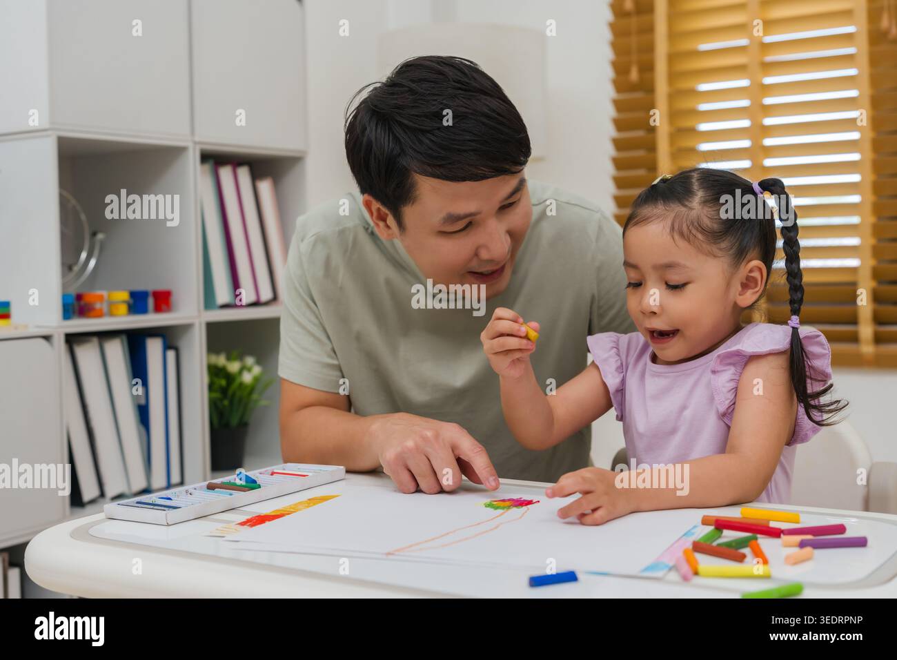 père et enfant fille dessin et peinture avec des pastels à l'huile colorés sur papier à la maison Banque D'Images