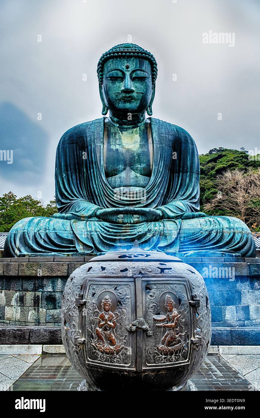 KAMAKURA, JAPON - 24 DÉCEMBRE 2025 : une grande urne d'encens avec de la fumée se dresse devant le géant Daibatsu en bronze, ou Bouddha géant, au Shojosen-ji; Banque D'Images