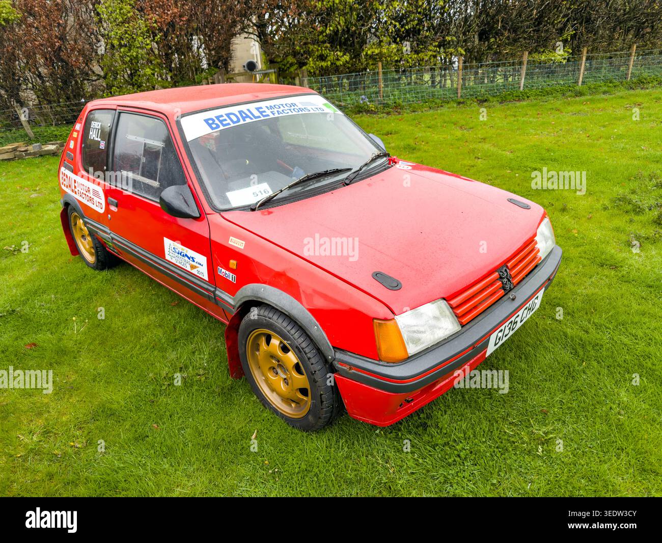 Voiture de rallye Red Peugeot 205 avec modifications de sport automobile et bande solaire de parrainage garée sur un terrain en herbe au Royaume-Uni Banque D'Images