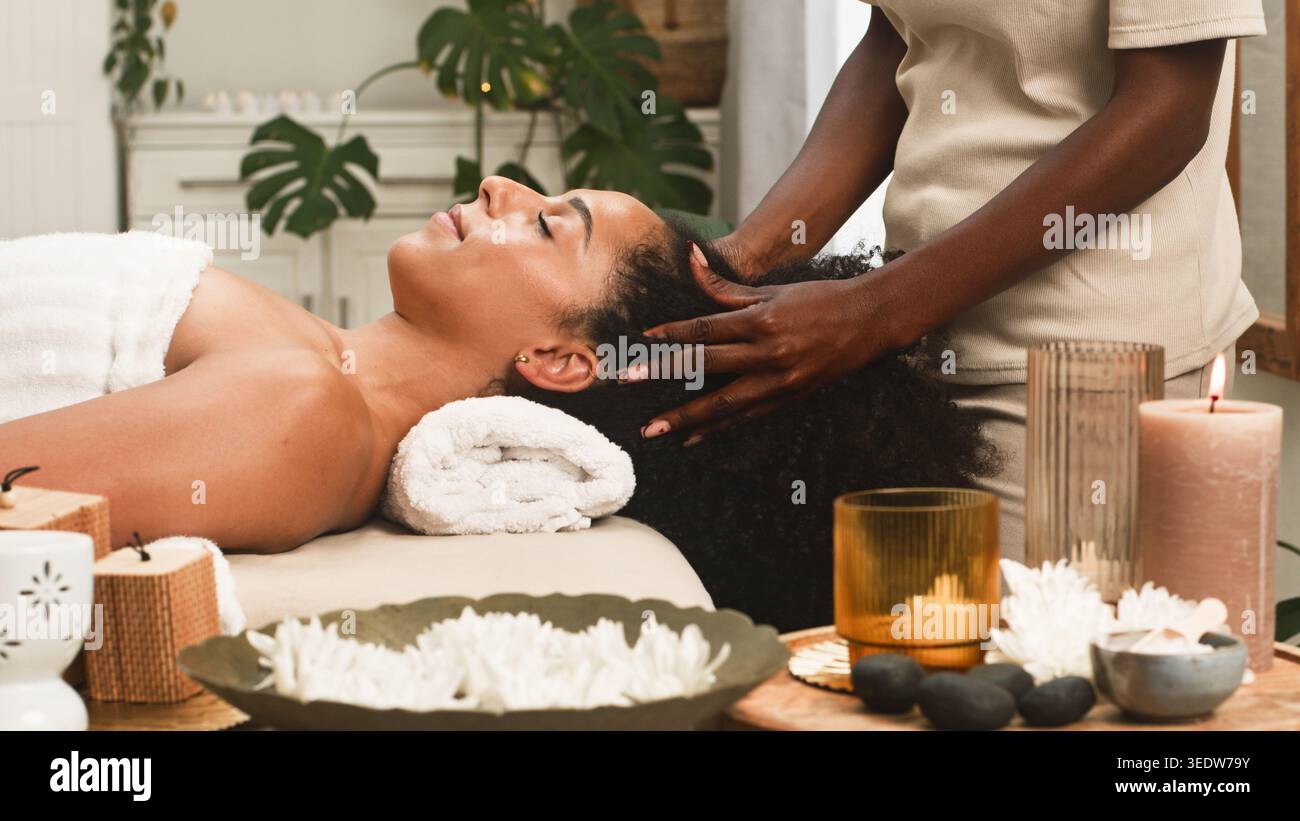 Massage relaxant de la tête dans Un spa avec bougies, serviettes et aromathérapie pour le bien-être Banque D'Images