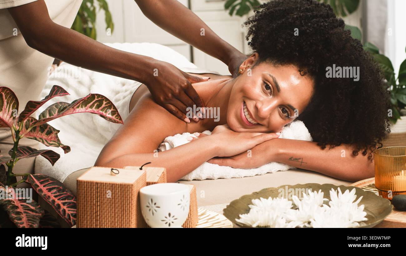 Séance de massage relaxant au spa : femme souriante recevant un soin du cou et des épaules dans un cadre de bien-être serein Banque D'Images