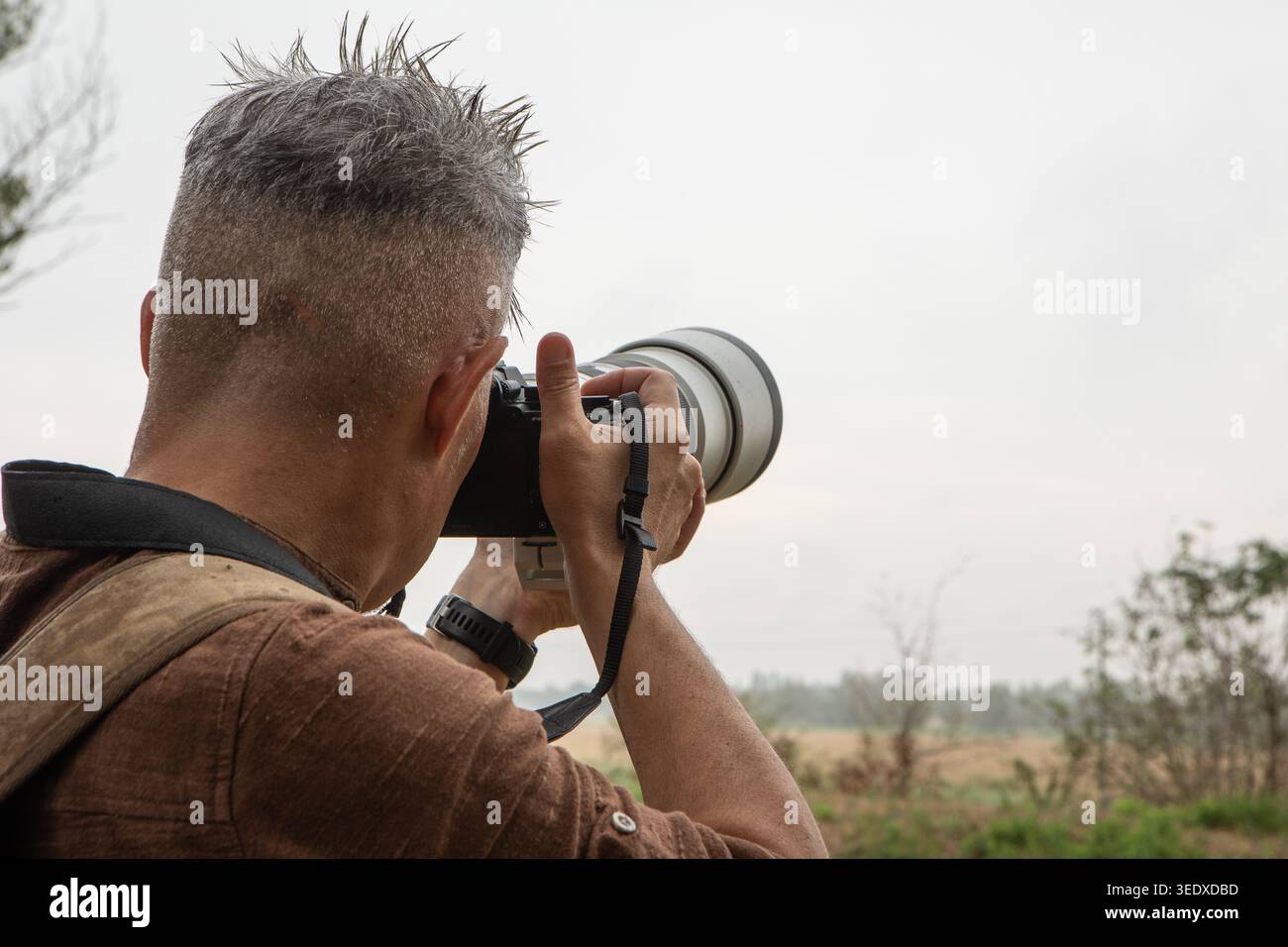 Photographe mettant au point un téléobjectif sur un paysage lointain dans un cadre extérieur Banque D'Images