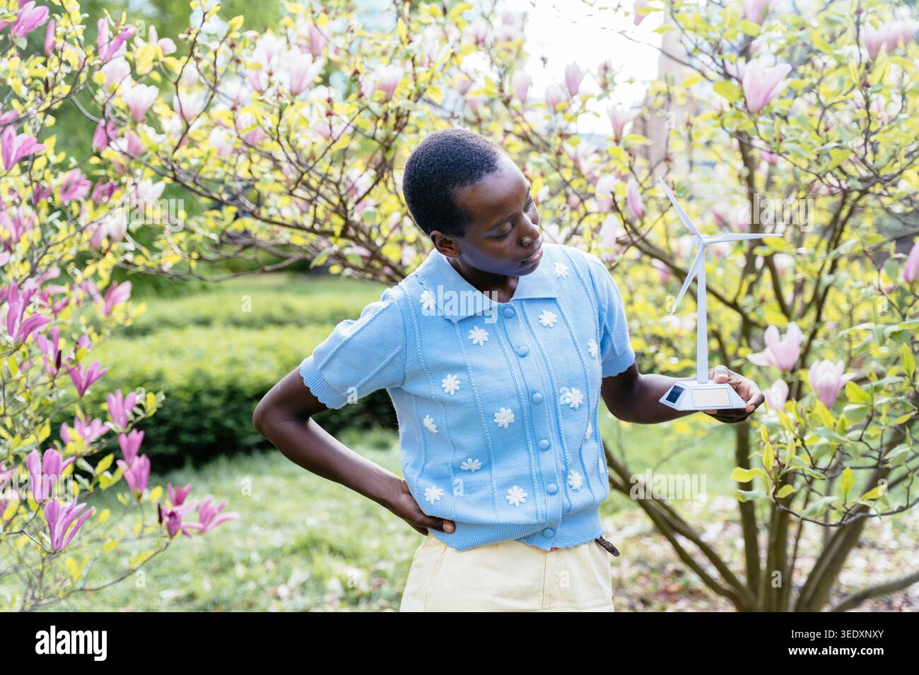 Femme africaine réfléchie avec modèle d'éolienne dans le jardin de printemps fleuri. Banque D'Images