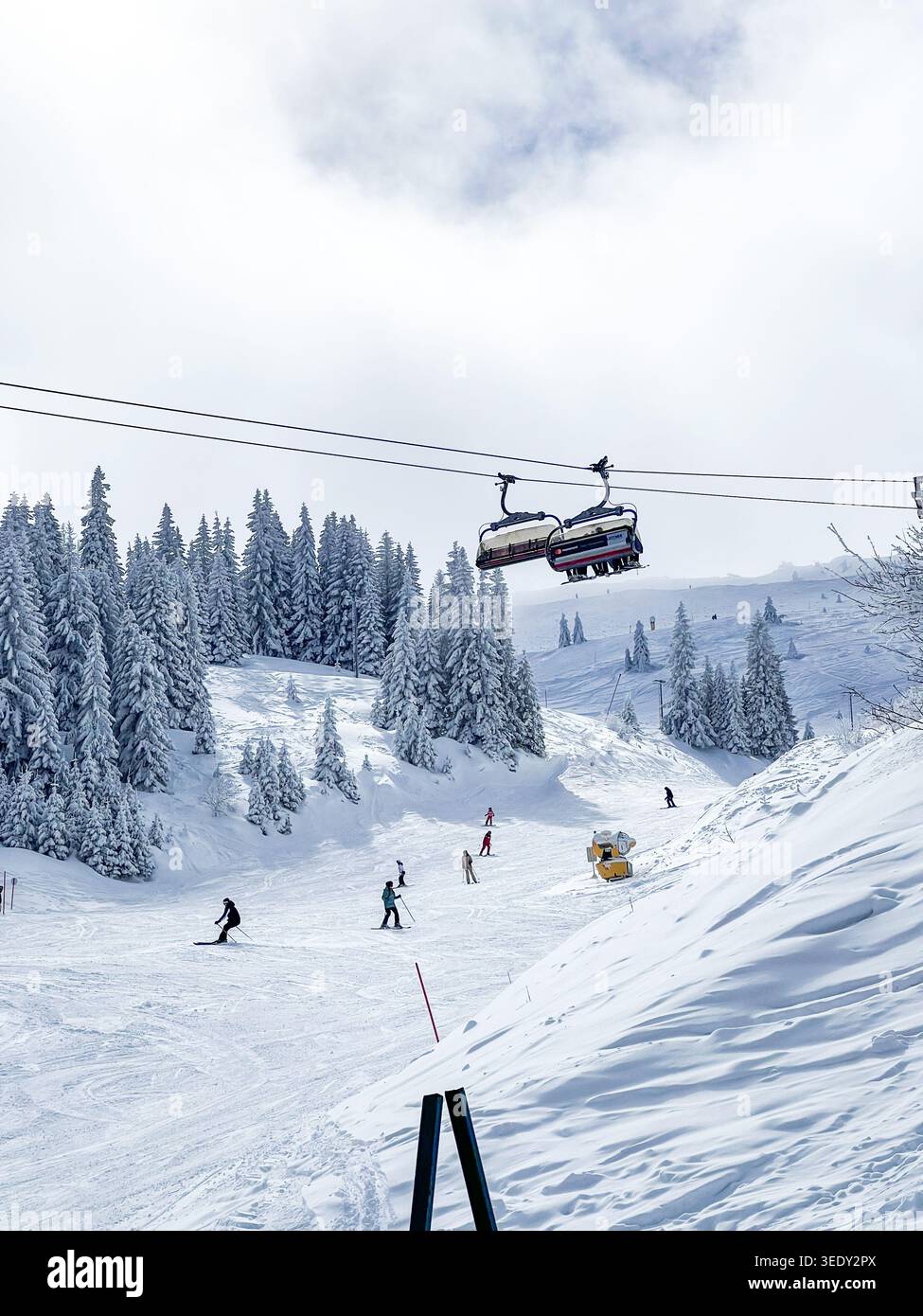 Piste de ski d'hiver avec skieurs, forêt de pins enneigés, et télésiège sur la montagne Jahorina en Bosnie-Herzégovine. - Image de stock capturée avec un smartphone