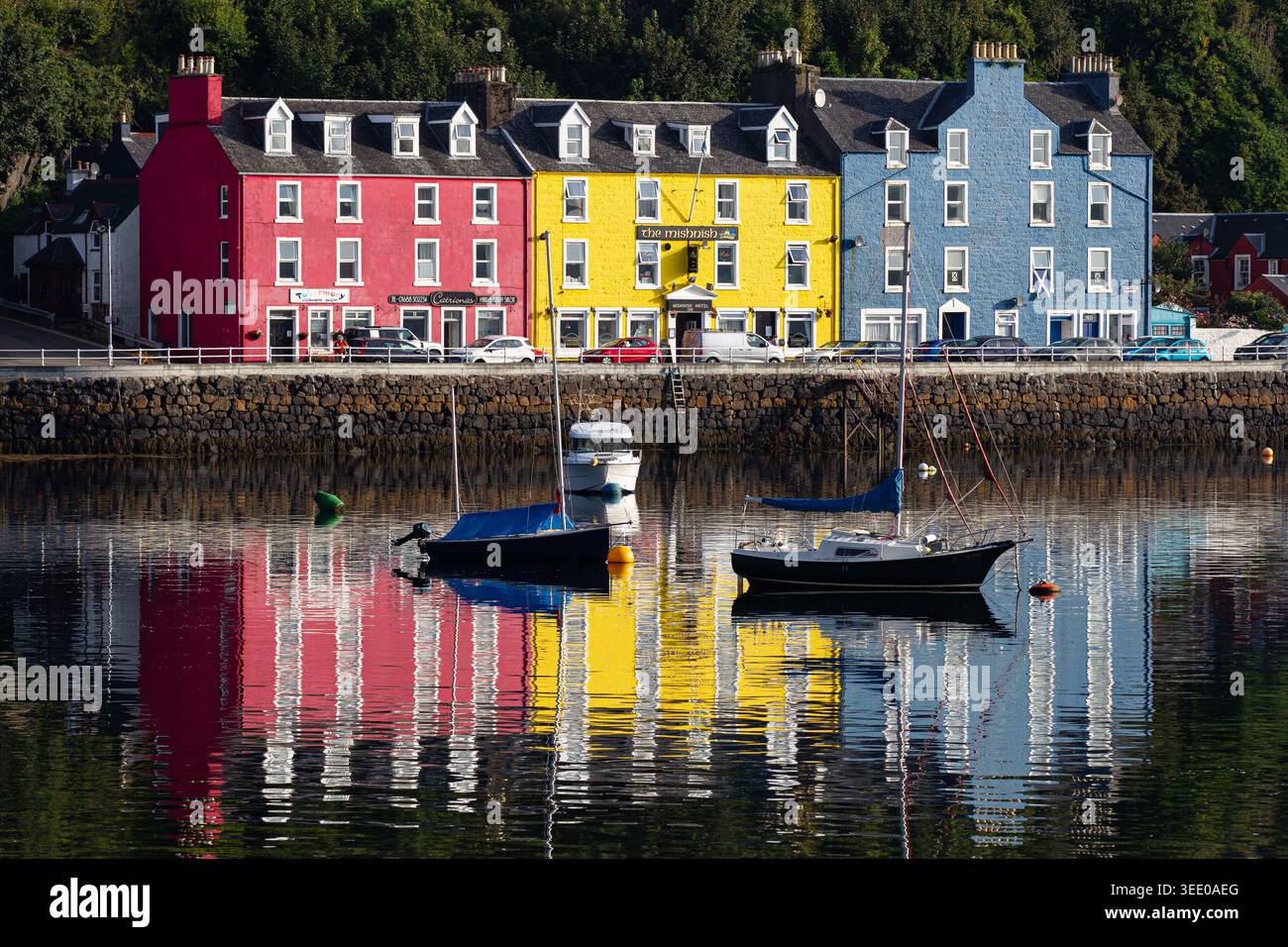 Vue sur les maisons colorées emblématiques le long du front de mer avec des bateaux amarrés dans le port et des reflets vibrants sur l'eau Tobermory, Écosse, Unit Banque D'Images