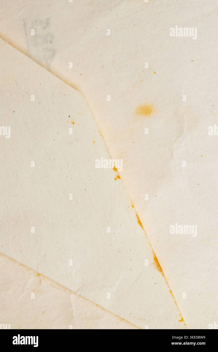 Vue rapprochée de vieux papiers jaunis montrant des imperfections naturelles comme des taches et des plis, évoquant un sens de l'histoire et de la nostalgie Banque D'Images