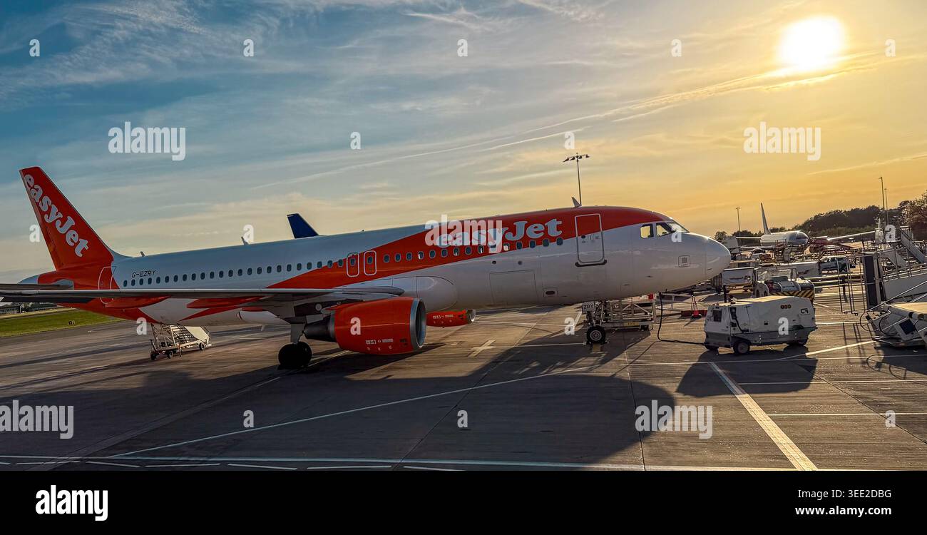 Un avion EasyJet stationné sur le tarmac d'un aéroport pendant un coucher de soleil à l'heure dorée avec un équipement de soutien au sol à proximité à l'aéroport de Bristol UK - Image de stock capturée avec un smartphone