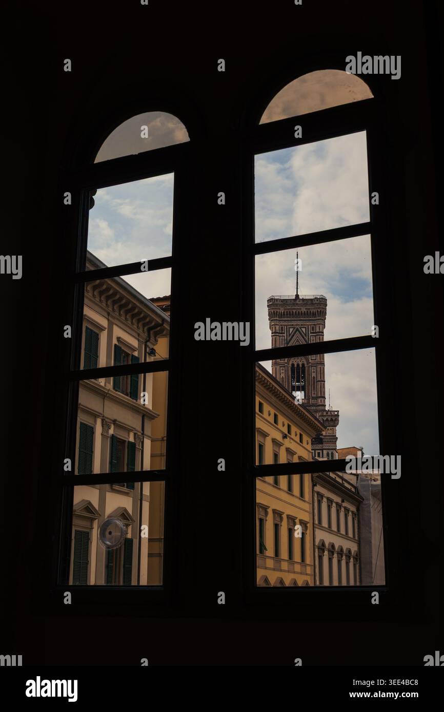 Une vue intérieure à travers une fenêtre sombre et voûtée à Florence, en Italie, donnant sur des bâtiments architecturaux historiques. La caractéristique principale est un secti Banque D'Images