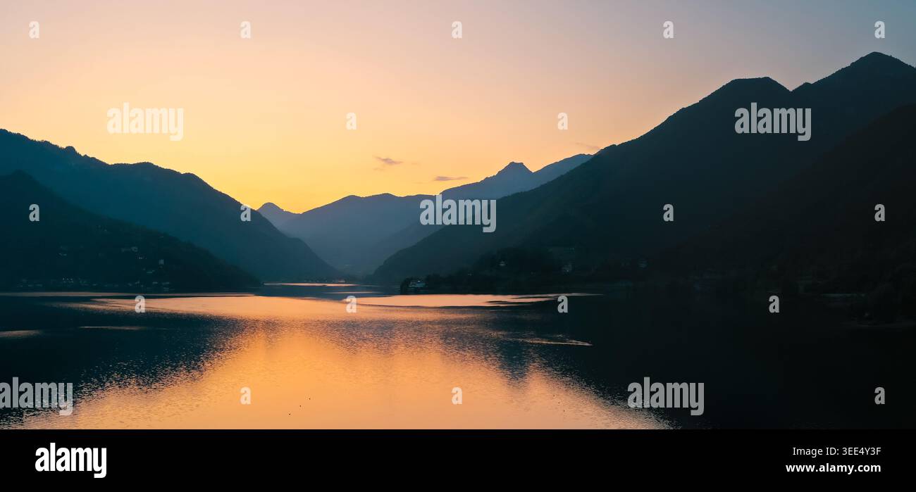 Coucher de soleil d'été sur Lago di Ledro dans le Trentin, Italie avec des reflets calmes et des silhouettes de montagne près de la ville de Ledro. Banque D'Images
