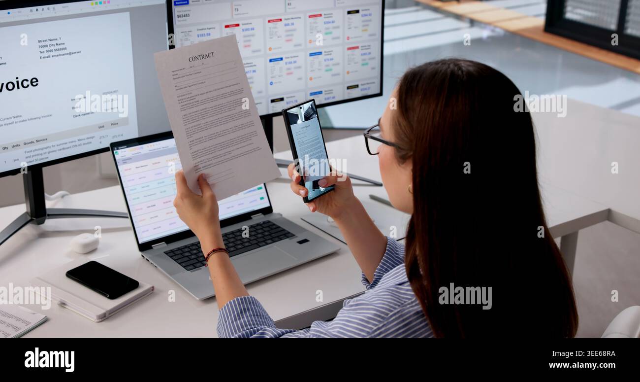 Office Manager utilise un smartphone pour scanner le contrat pour la vérification numérique. Banque D'Images