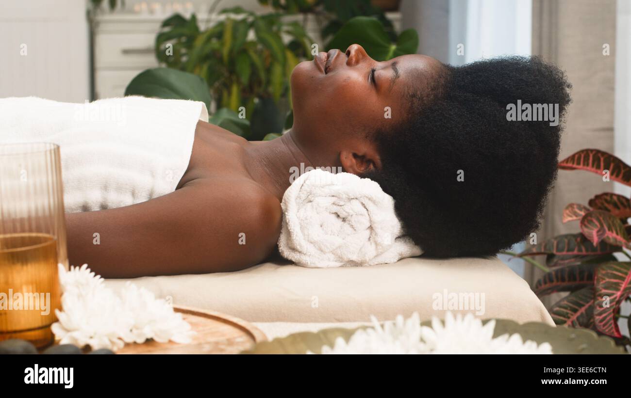 Femme détendue recevant un soin spa couchée sur une table de massage en éponge dans une chambre tranquille Banque D'Images