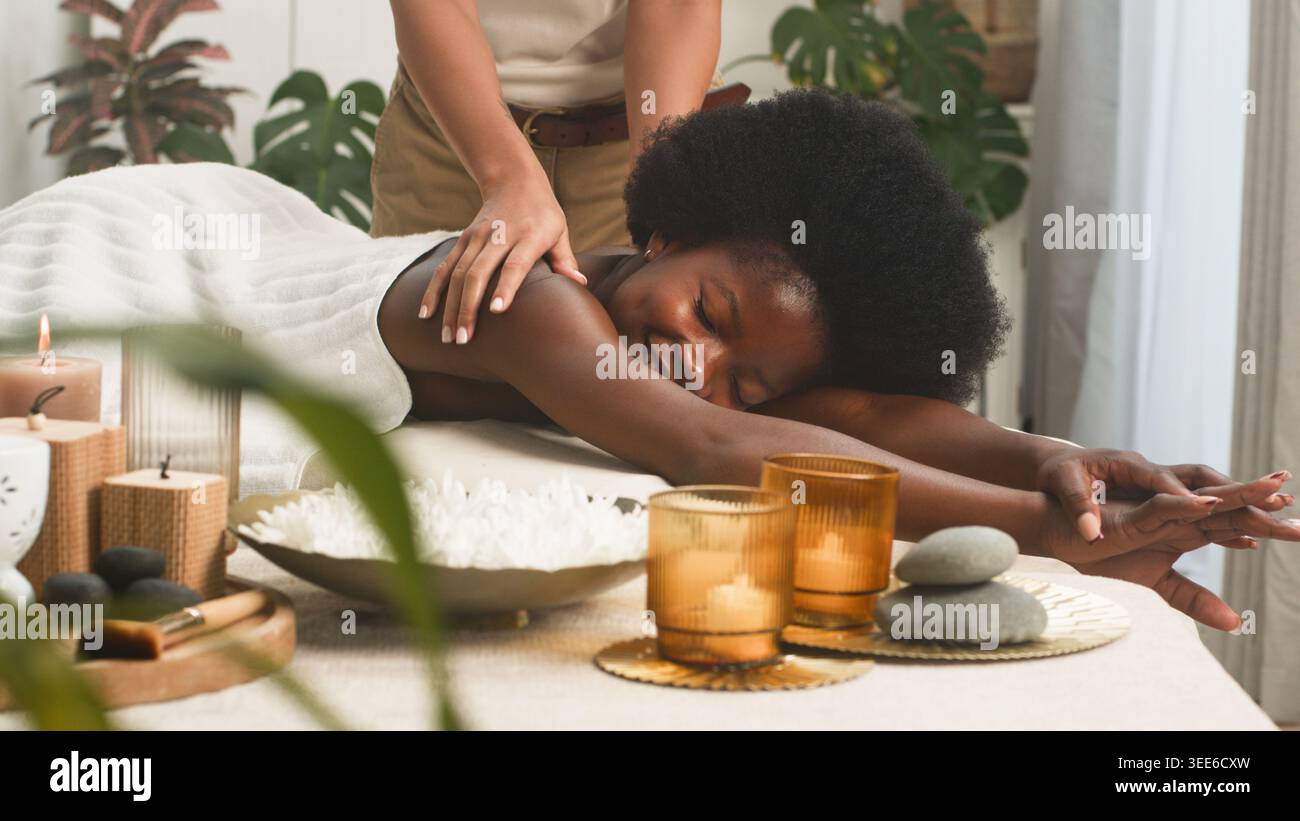 Séance de massage relaxante au spa avec femme souriante recevant un traitement d'aromathérapie dans la confortable salle de bien-être Banque D'Images