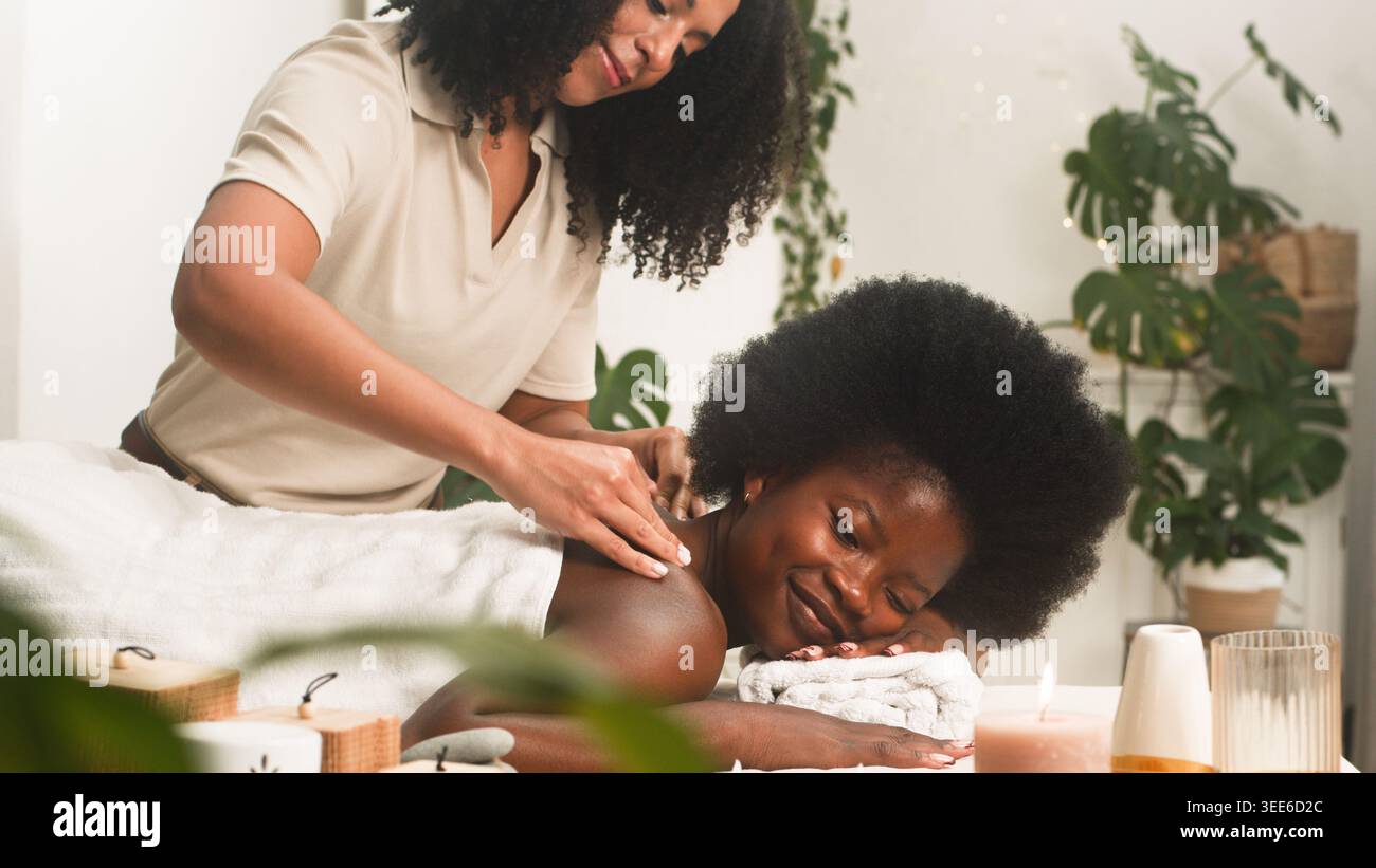 Massage relaxant au spa avec femme souriante recevant un massage des épaules dans la salle de bien-être calme Banque D'Images