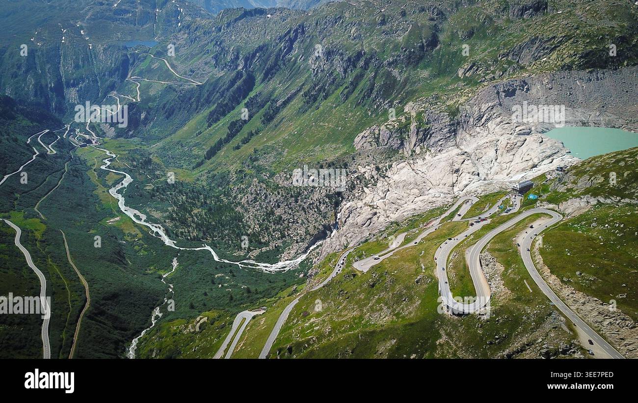 Vue aérienne du col de Furka avec ses virages emblématiques en épingle à cheveux sinueuse, le glacier du Rhône et un lac de montagne turquoise niché dans les Alpes suisses près d'Oberg Banque D'Images