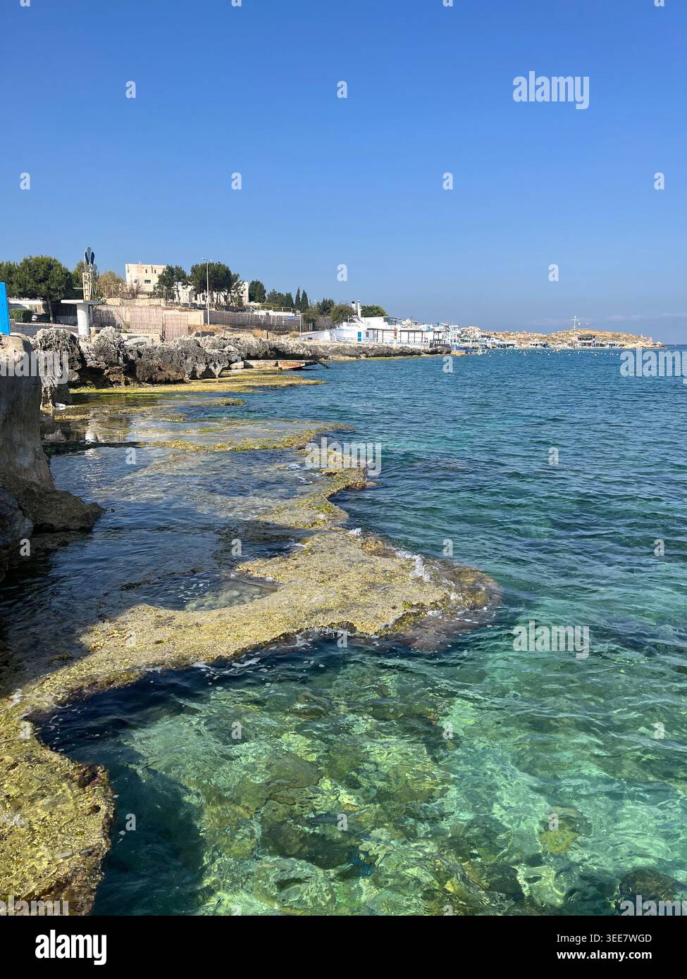 L'eau de mer turquoise limpide se lavant sur les anciens marais salants phéniciens et les piscines taillées dans la roche le long d'une côte méditerranéenne rocheuse sous un SK bleu vif - Image de stock capturée avec un smartphone