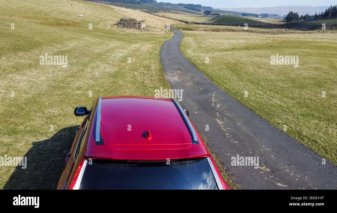 Vue aérienne d'une voiture rouge sur une route sinueuse de landes qui s'étend dans le paysage de Wensleydale Banque D'Images