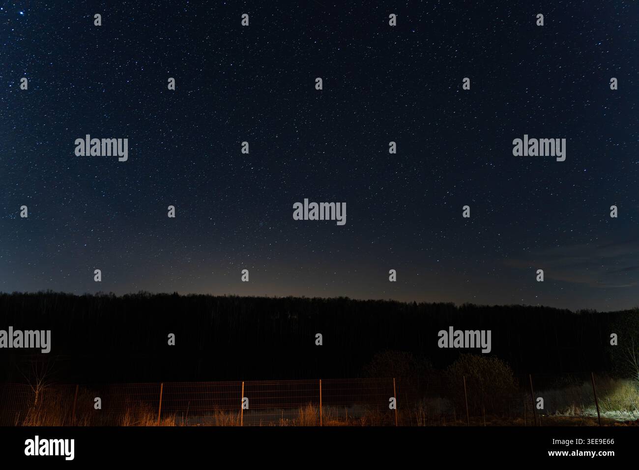 Ciel étoilé au-dessus de la clôture rurale, Soft Horizon Glow silhouettes lointaine, champ vide et clôture en bois usée en premier plan, atmosphère calme Banque D'Images