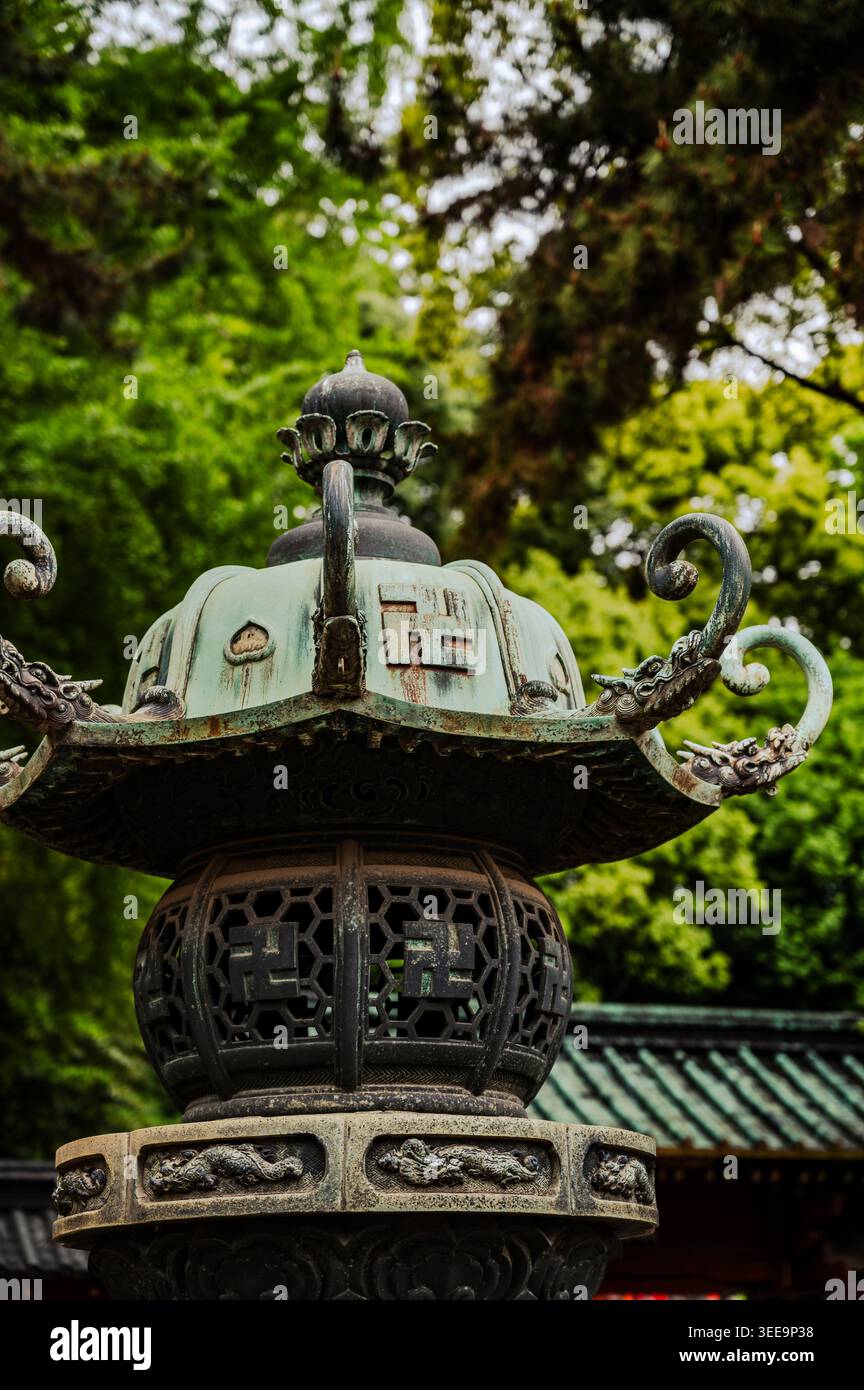 Lanterne décorative en bronze tōrō avec embouts courbés ornés et motifs traditionnels au sanctuaire Nezu, quartier Bunkyō, Tokyo, Japon Banque D'Images