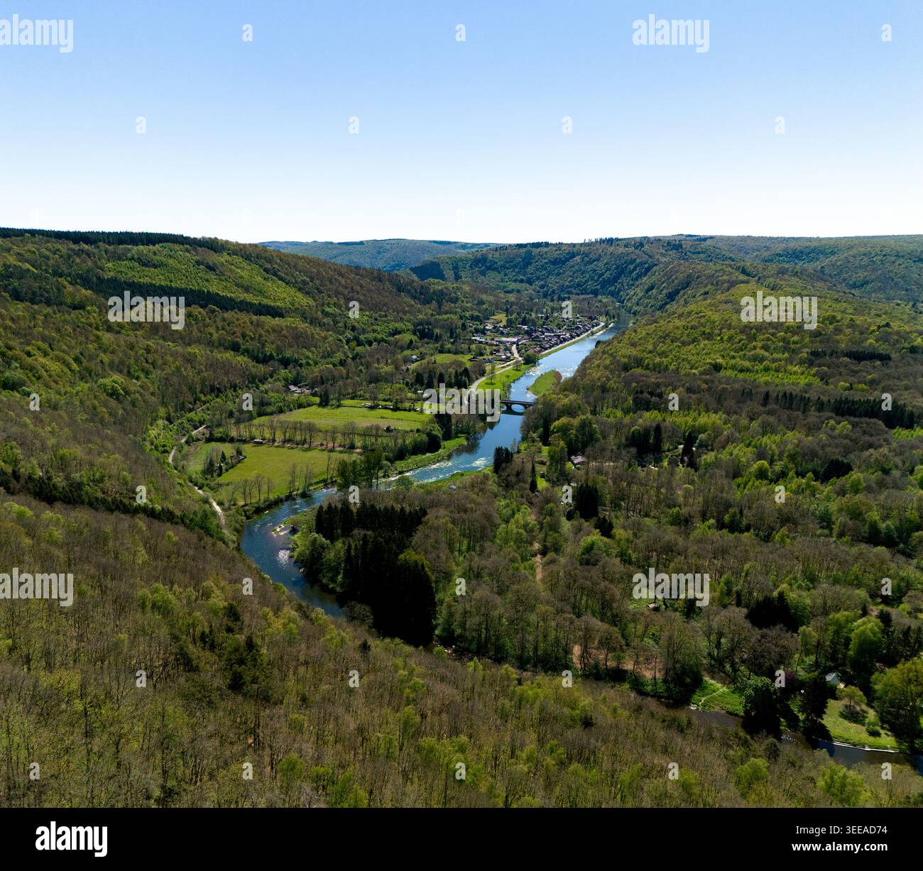 Vue aérienne de la rivière Semoy serpentant à travers les collines boisées luxuriantes de la vallée des Ardennes près d'un petit village sous un ciel bleu clair les Hautes-R. Banque D'Images