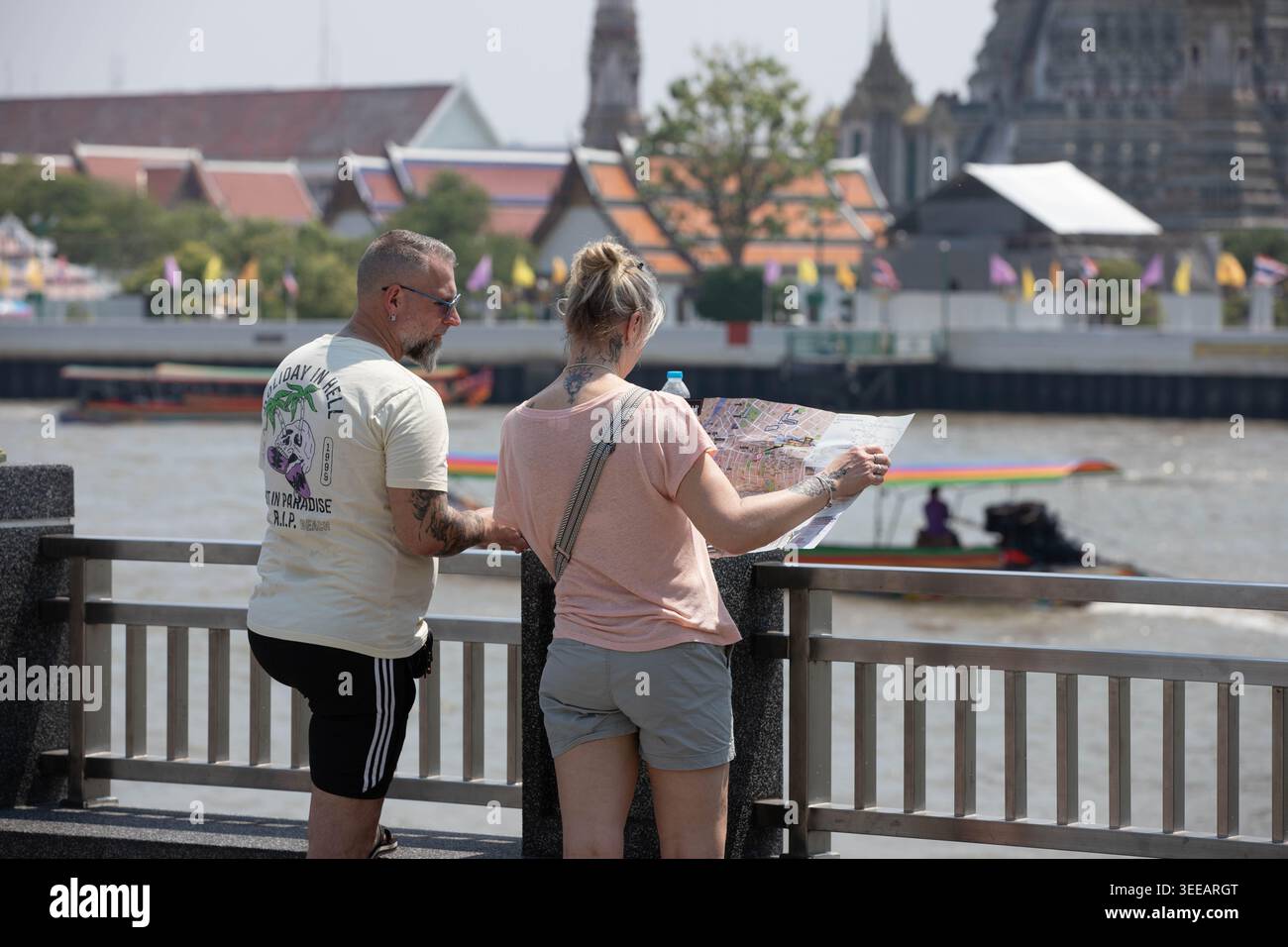 BANGKOK, THAÏLANDE-APR 5, 2026 : couple de touristes lisant la carte touristique, touristes marchant à travers l'atmosphère urbaine locale, vue arrière, Tha Tien. Banque D'Images